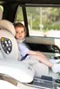 A young child sits in a car seat in the back seat of a car. Voir les images du produit
