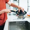 A person is draining water from a pot into a sink. Voir les images du produit