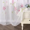 A sheer curtain with a floral pattern draped over a bedside table. Produktbild-Vorschau