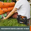 A person is using a portable air compressor to inflate an orange inflatable object on a grassy lawn. Produktbild-Vorschau