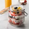 A glass jar filled with layers of granola, yogurt, strawberries, blueberries, and sliced peaches, with a glass of orange juice in the background. Anteprima dell’immagine prodotto