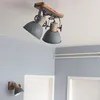 A ceiling light fixture with two adjustable lamps and a wall sconce are shown in a room with light blue walls. Anteprima dell’immagine prodotto
