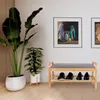 A shoe rack with a bench and shoes on it, placed in a hallway with plants and artwork on the wall. Produktbild-Vorschau