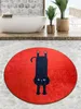 A round bath mat with a black cat design is placed on a tiled floor in front of a bathtub. Produktbild-Vorschau