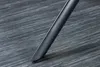 A close-up shot of a dark-colored chair leg resting on a textured, dark gray surface. Produktbild-Vorschau