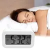 A woman sleeping peacefully in bed with a digital alarm clock in the foreground. Voir les images du produit