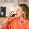A woman is drinking coffee from a glass. Produktbild-Vorschau