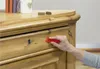 A hand is using a red tool to repair a wooden drawer on a piece of furniture. Podgląd zdjęcia produktu
