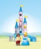A toy castle with two figures in front of it, set against a sky and grassy background. Produktbild-Vorschau