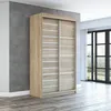 A modern sliding door wardrobe in a room with a concrete wall and wooden floor. Produktbild-Vorschau