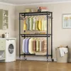 A laundry room or closet with clothing on a rack and a washing machine. Voir les images du produit