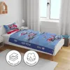 A child's bed with bedding featuring a police and fire truck motif, set in a bedroom with a window and curtains. Produktbild-Vorschau