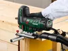A person is using a jigsaw to cut a piece of wood, with a vacuum hose attached for dust collection. Produktbild-Vorschau