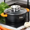 A black pot with orange handles and a glass lid sits on a black stovetop. Ingredients like carrots, pasta, and peppercorns are visible around the pot. Voir les images du produit