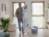 A man stands next to an ironing board in a room with large windows and plants. Náhľad obrázku produktu