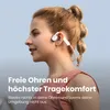 A woman with her hair in a ponytail is wearing white and pink headphones while outdoors. Produktbild-Vorschau