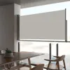 A dining area with a table and chairs, with a retractable side awning covering a large window overlooking a cloudy sky. Voir les images du produit