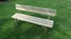 A wooden garden bench sits on a grassy lawn. Produktbild-Vorschau