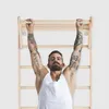 A man is hanging from a wooden wall bar. Produktbild-Vorschau