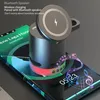 A close-up of a cylindrical Bluetooth speaker with a wireless charging pad on top, placed on a smartphone screen displaying music and time. Produktbild-Vorschau