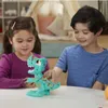 Two children are playing with a toy dinosaur on a table. Produktbild-Vorschau