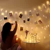 A woman is decorating a wall with photos attached to a string of fairy lights. Produktbild-Vorschau