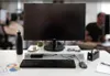 A desk setup with a monitor, keyboard, mouse, and other office supplies. Voir les images du produit