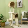 A cat tree is placed in a living room setting next to a chair and a plant. Podgląd zdjęcia produktu