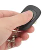 A hand holding a black remote control with a silver keychain attached. Náhled obrázku produktu