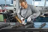 A man is using a Bosch angle grinder in a workshop setting. Voir les images du produit