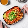 A person is eating from a metal lunchbox filled with food, with a small cup of sauce nearby. Podgląd zdjęcia produktu