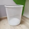 A white mesh waste bin sits on a wooden floor next to a wall with gray and green sections. Produktbild-Vorschau