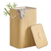 A bamboo laundry basket with its lid open, placed on a white background. Some bamboo leaves are visible on the left side. Náhled obrázku produktu