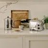 A kitchen counter scene with a toaster, kettle, mug, and toast. Anteprima dell’immagine prodotto