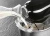 Milk being poured from a glass jug into a black kitchen appliance. Produktbild-Vorschau