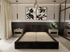 A modern bedroom with a black upholstered bed frame, two bedside tables, and abstract art on the wall. Produktbild-Vorschau