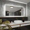 A modern bathroom vanity with a large LED-lit mirror, a white vessel sink, and decorative elements. Produktbild-Vorschau