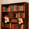 A wooden bookshelf filled with books, featuring two illuminated ghost-like figures wearing Santa hats and reading books. Produktbild-Vorschau