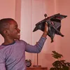 A young boy is happily playing with a Batman action figure in a room. Anteprima dell’immagine prodotto