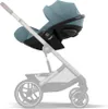A teal and black baby car seat attached to a gray stroller frame, shown against a white background. Produktbild-Vorschau