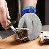 A person is shucking an oyster on a wooden cutting board while wearing a protective glove. Produktbild-Vorschau