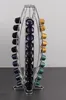 A rotating coffee capsule holder filled with various colored capsules, placed on a dark surface with a light gray background. Náhľad obrázku produktu