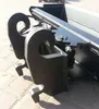 A close-up view of heavy-duty black metal hooks, likely part of an excavator or loader attachment, resting on a paved surface. Produktbild-Vorschau