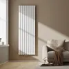 A modern living room with a vertical designer radiator, a sofa with a blanket, and a window. Produktbild-Vorschau