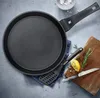 A frying pan is shown on a countertop with cooking utensils and ingredients. Náhľad obrázku produktu