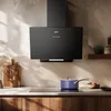 A modern kitchen scene featuring a black range hood above a stovetop with a blue pot. Voir les images du produit