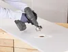 A person is using a drill with a hole saw attachment to cut a hole in a white surface. Produktbild-Vorschau