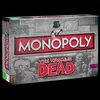 The image shows the front of a Monopoly The Walking Dead board game box, presented at an angle against a black background. Náhled obrázku produktu