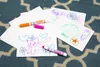 Children's drawings on white paper with Crayola markers scattered on a blue and white patterned rug. Voir les images du produit
