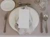 A table setting with a menu, plates, and cutlery. Produktbild-Vorschau